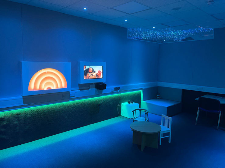 Features of the room include: color lighting, low level LED lights, VRA screens and a high contrast rainbow reward. Removable VRA toy rewards, a vibro chair with additional ceiling speaker and fiber optic lighting. The whole side of the room can light up - in addition to just the VRA screen - supporting those who are developing understanding of the task or for conditioning purposes, increasing motivation or who for those who have visual impairment. The screens and VRA rainbow reward are securely encased to limit risk.