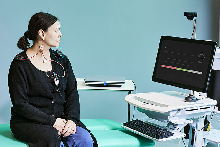 Le patient était assis sur un lit d'examen avec un montage d'électrodes cVEMP et regardait vers un écran d'ordinateur avec un moniteur EMG. L’Interacoustics Eclipse repose sur une table à côté du patient.