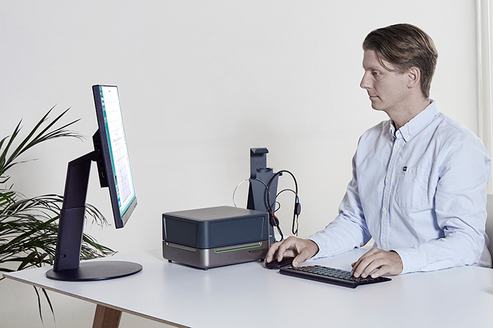 Clinician sitting at desk with the Affinity Compact resting on the desk. The clinician is operating the Affinity Compact’s HIT software module.