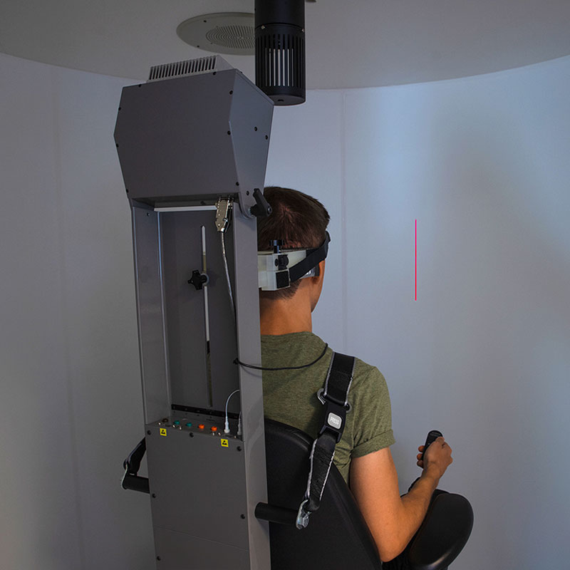 Male patient performing subjective visual vertical test in a rotary chair