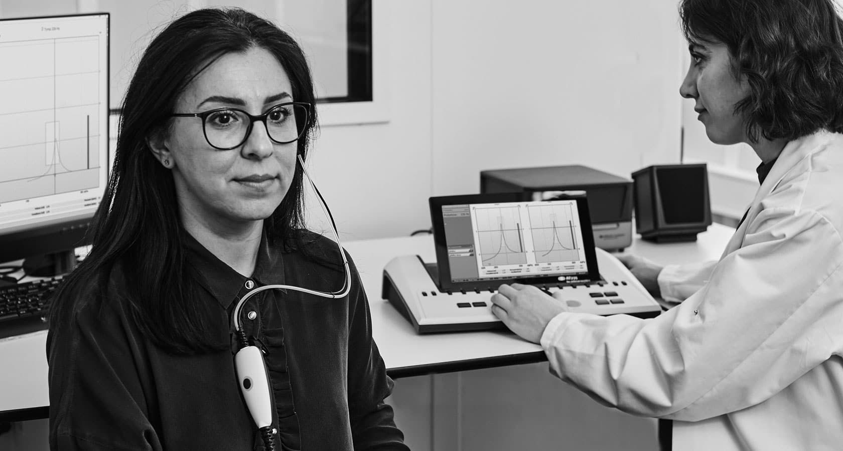 Female clinician using clinical probe to perform middle ear assessment on young female patient