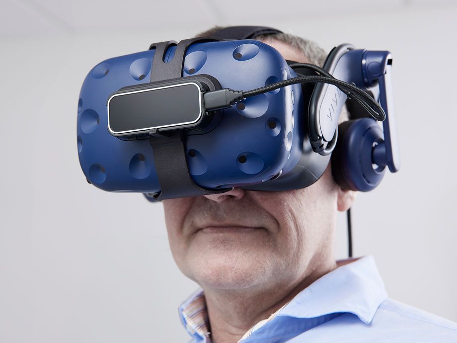 Person in blue shirt wearing VIVE VR goggles